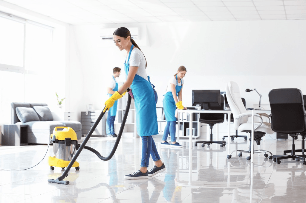 Cleaning crew vacuuming and wiping down desks in a commercial office